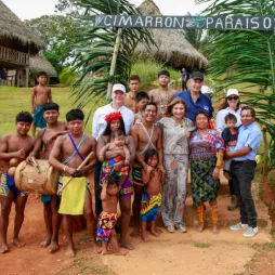 Un grupo de personas, incluidos adultos y niños, están juntos bajo un letrero que dice 'Cimarron Paraiso'